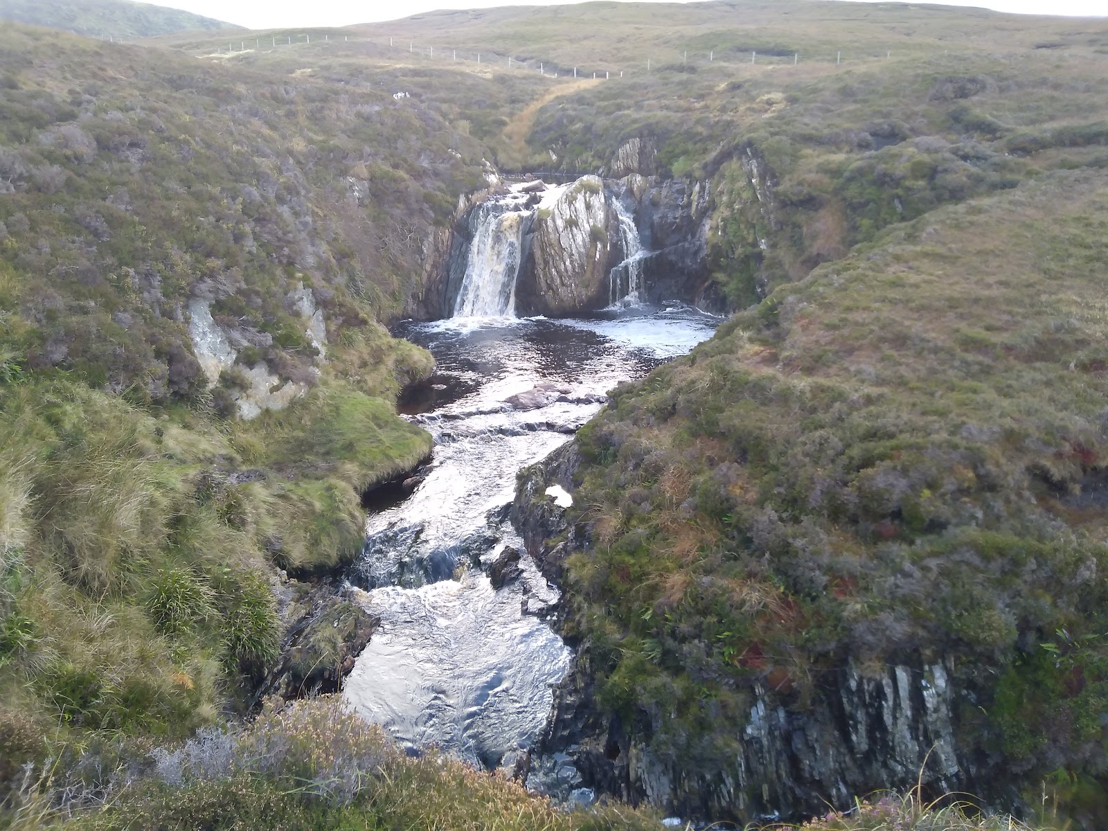 Ramnahol, the waterfall on the Burn of Lunklet, falling into a rocky pool below heathery banks.