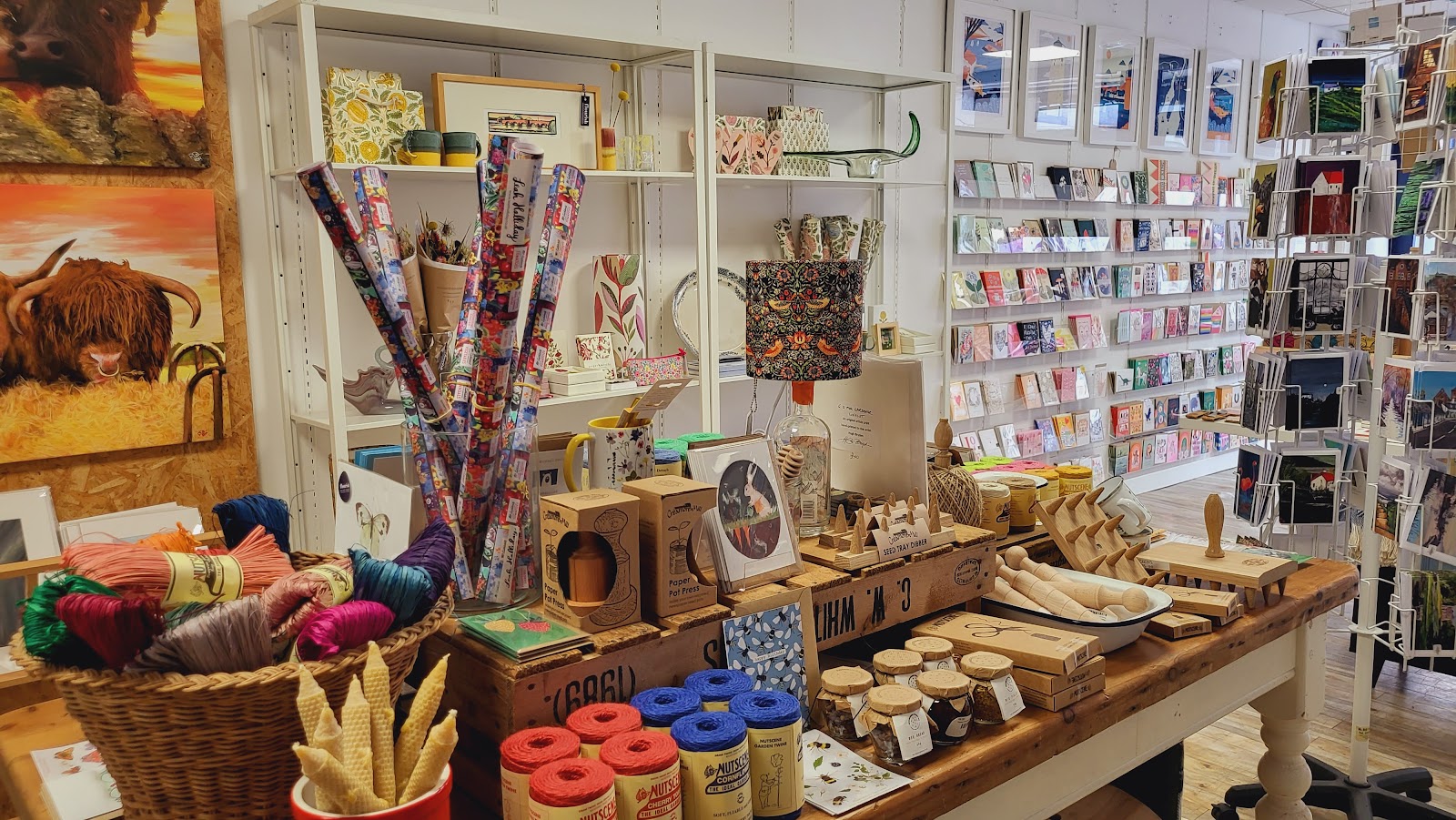 Gift shop table with wrapping paper, Nutscene twine, seed tray dibbers and Highland cow paintings