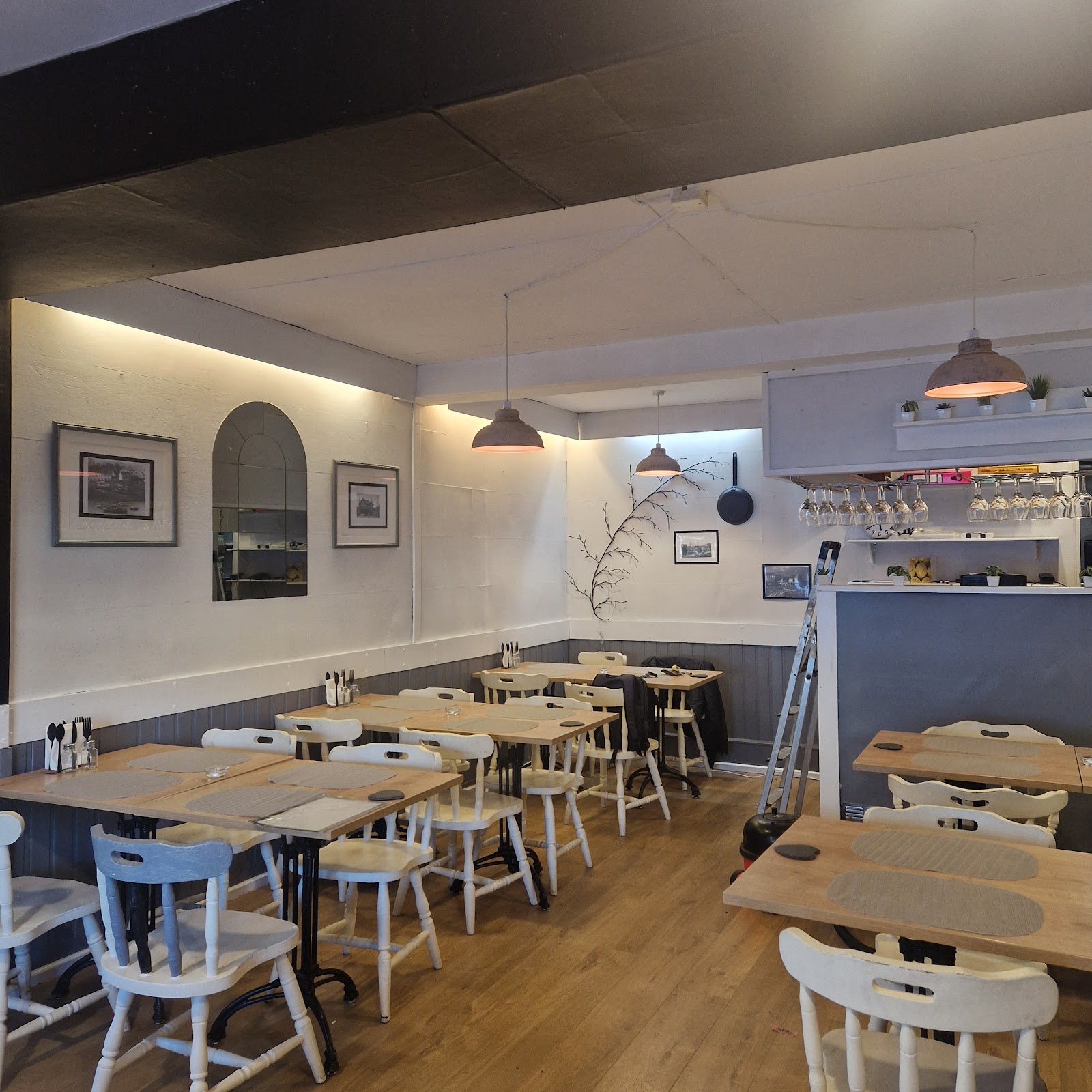 Empty café dining room with pale wooden tables, white chairs and hanging pendant lights