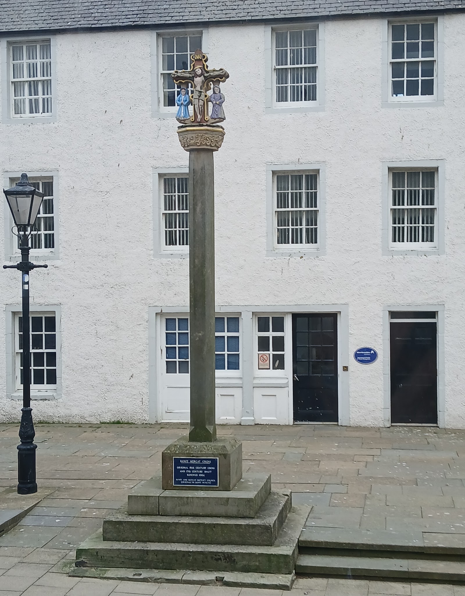 The mercat cross in Banff before a white-harled Georgian house.