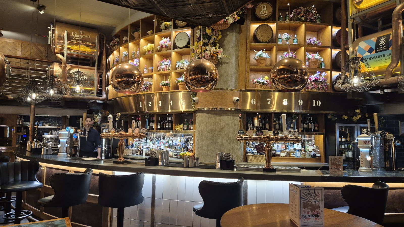 The long bar at Brewhemia, lit by copper and low lamps.