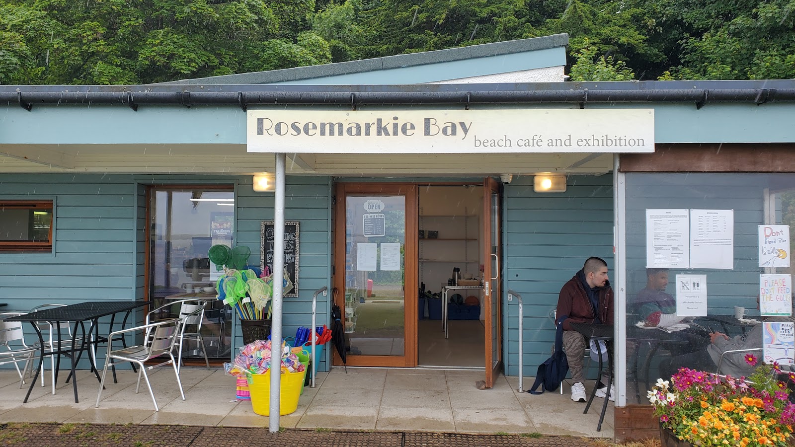 The Rosemarkie Beach Cafe, a small blue timber cafe with its name over the door and tables outside.