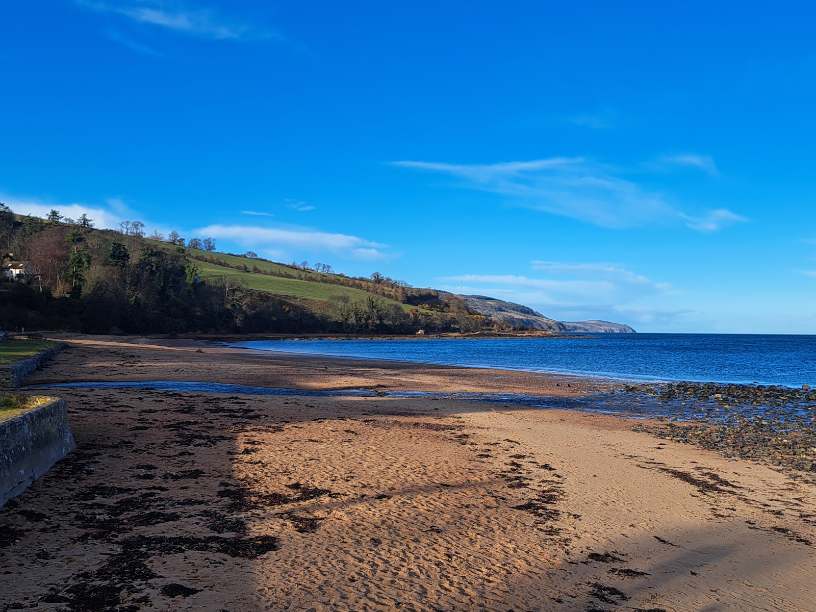 Rosemarkie's sands in low sun, wooded cliffs running out along the blue Moray Firth.