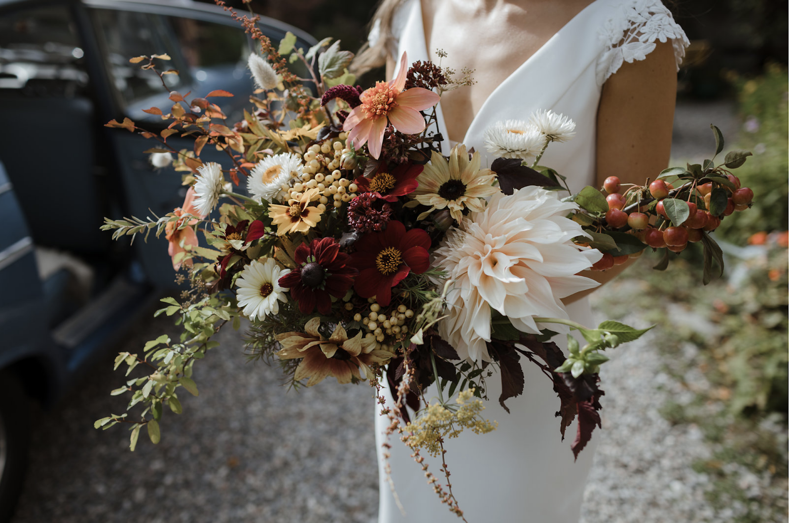 A wild bridal bouquet of pale dahlias, grasses, daisies and berries by Wild Gorse Studio.