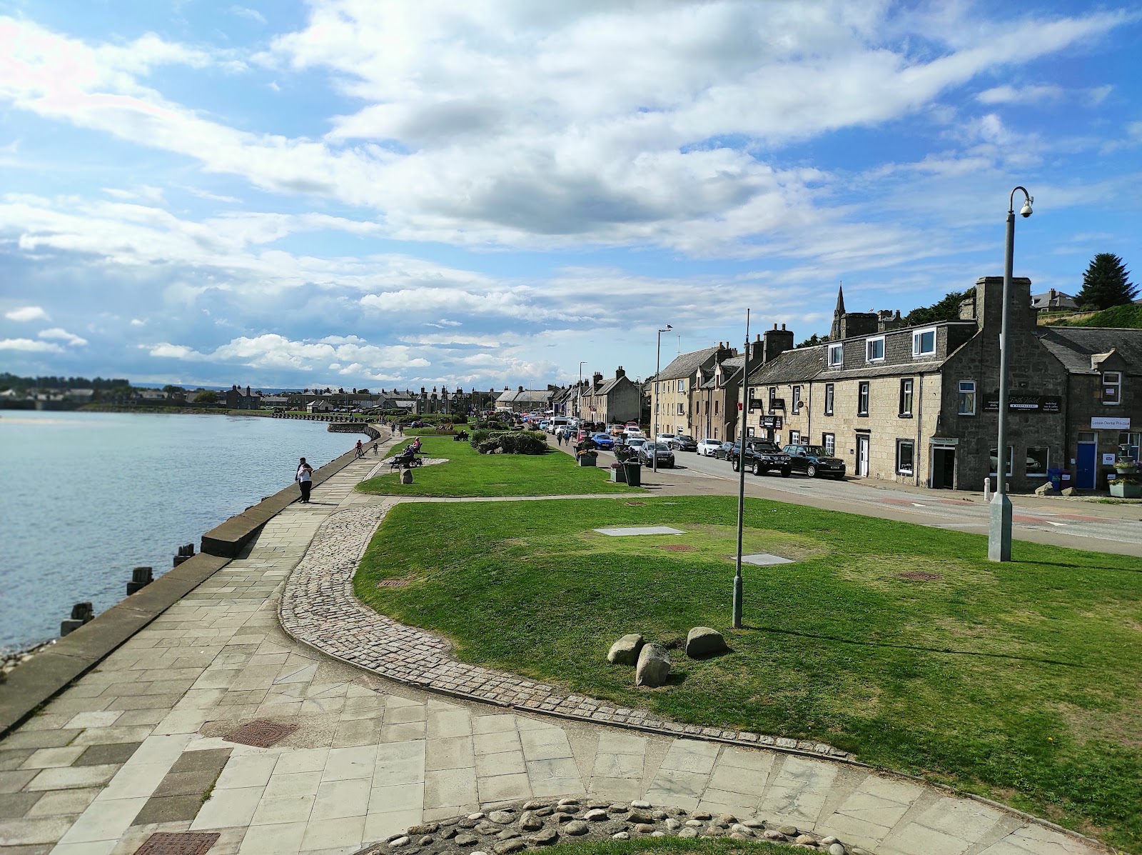 Grassy promenade beside the Firth, stone houses and shops lining the road