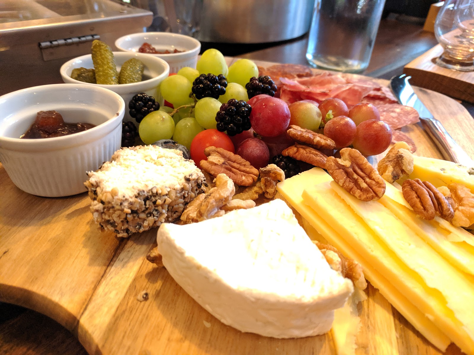 Cheese board with brie, cured meats, grapes, pecans, chutney and gherkins