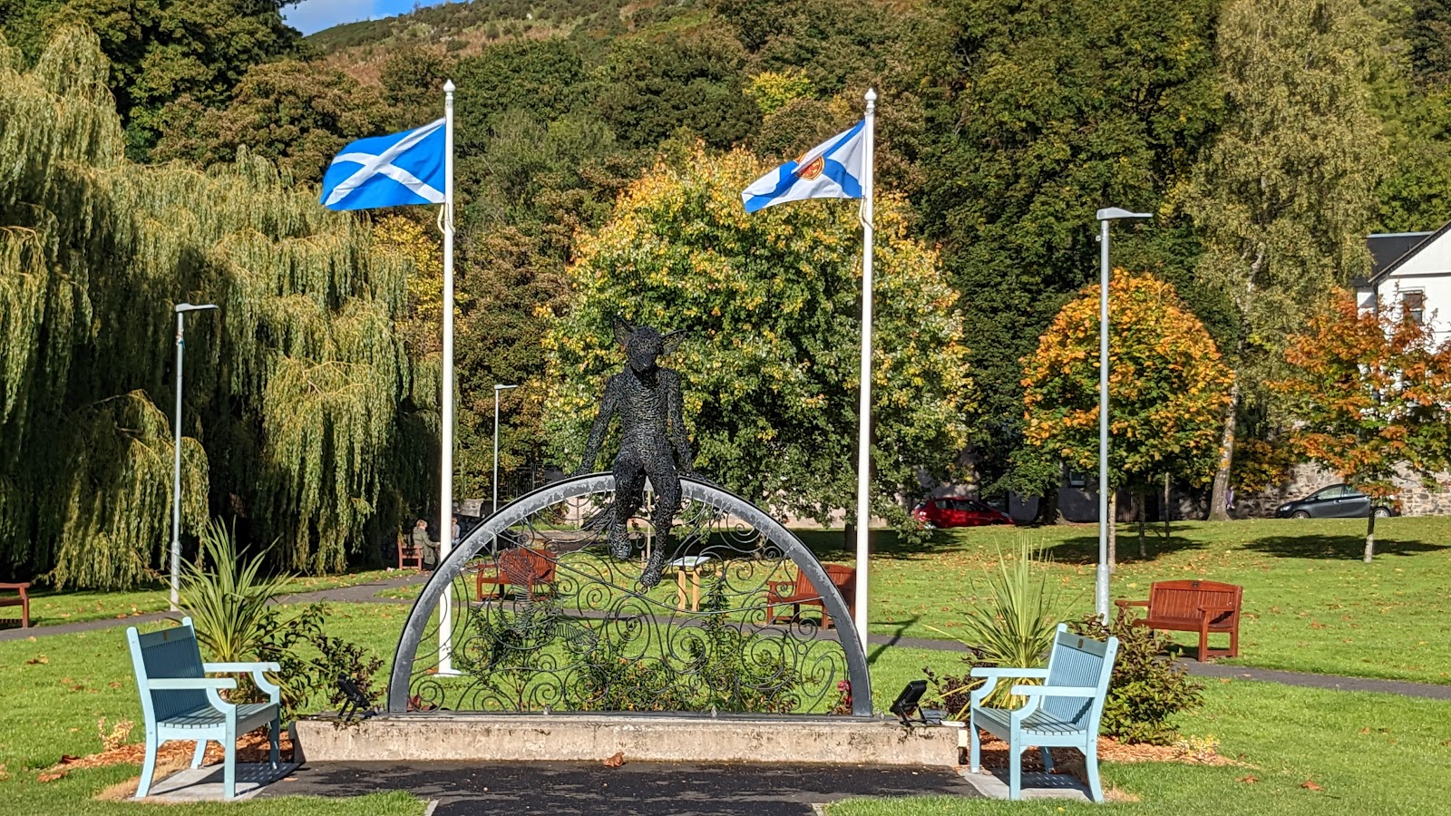 Wire cat sculpture atop an archway between a Saltire and burgh flag
