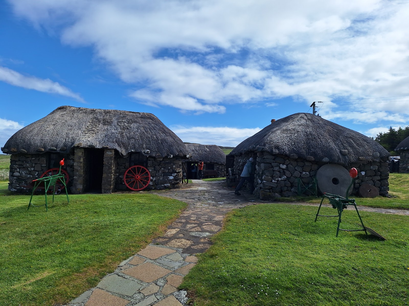Thatched stone cottages with cart wheels and old farm tools on display