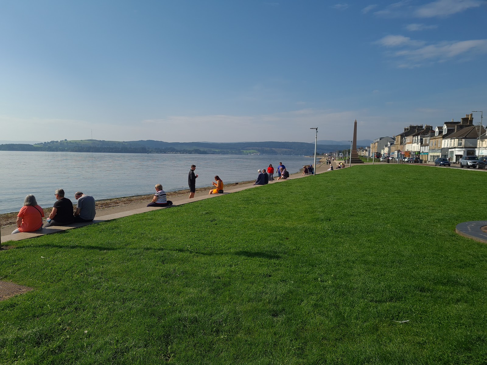 People on the grass above the seafront, looking over the Firth of Clyde.
