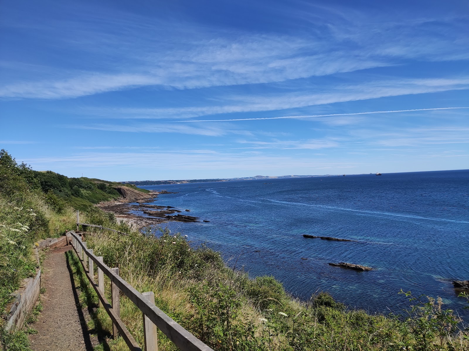 The Fife Coastal Path, a railed path along a green cliff above a blue sea.