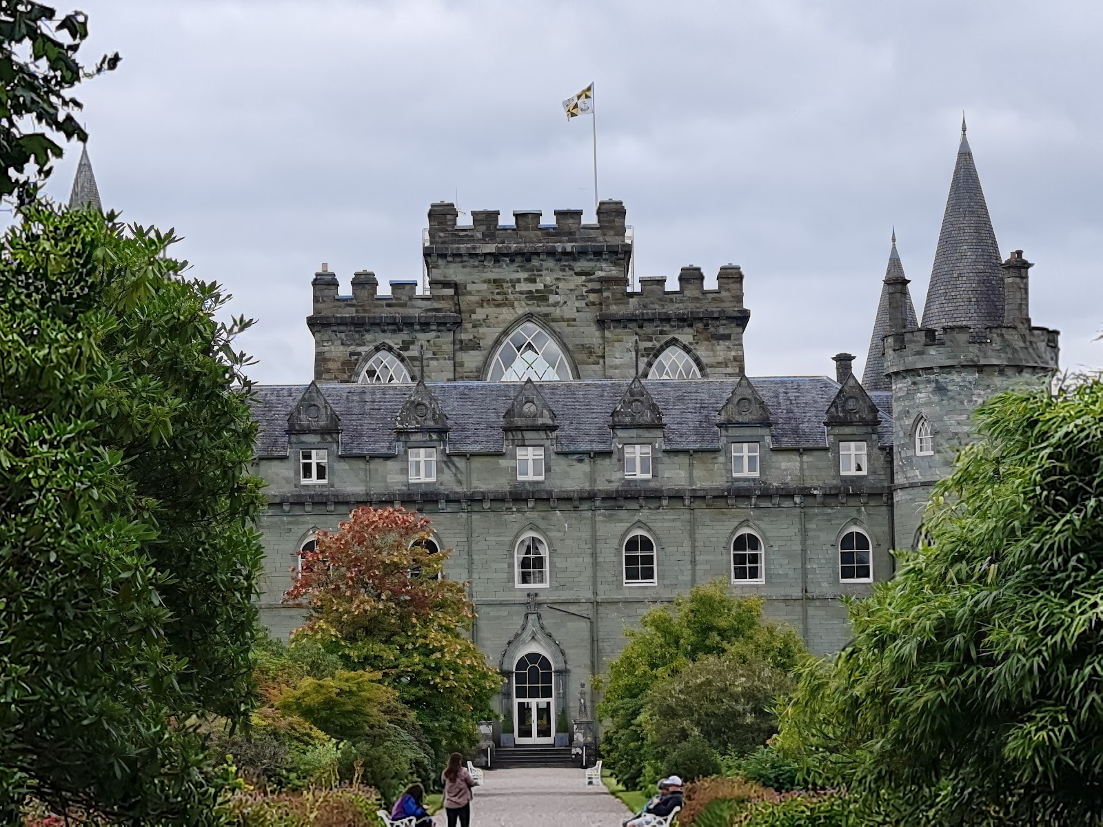 Inveraray Castle's turrets and flag rise above manicured garden hedges