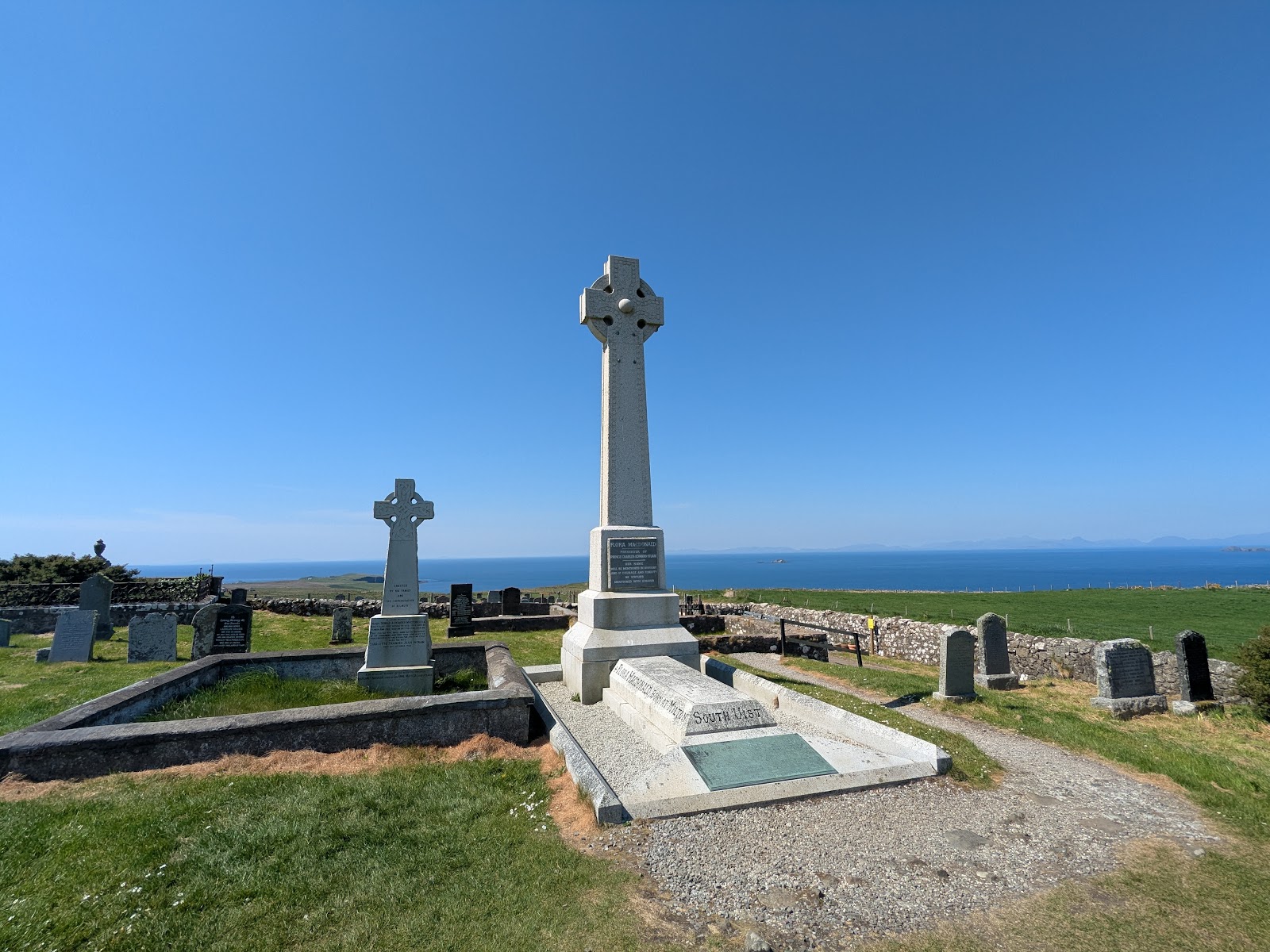 The granite Celtic cross over Flora MacDonald's grave in Kilmuir burial ground, with the Minch behind it.