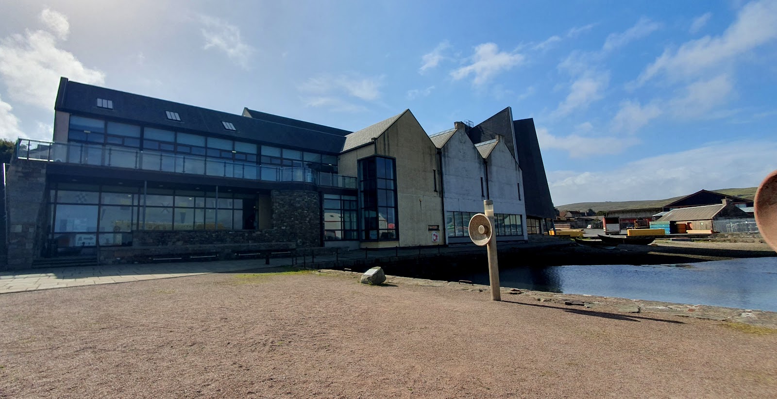 Modern gabled harbourside building with wooden boats moored beside the quay