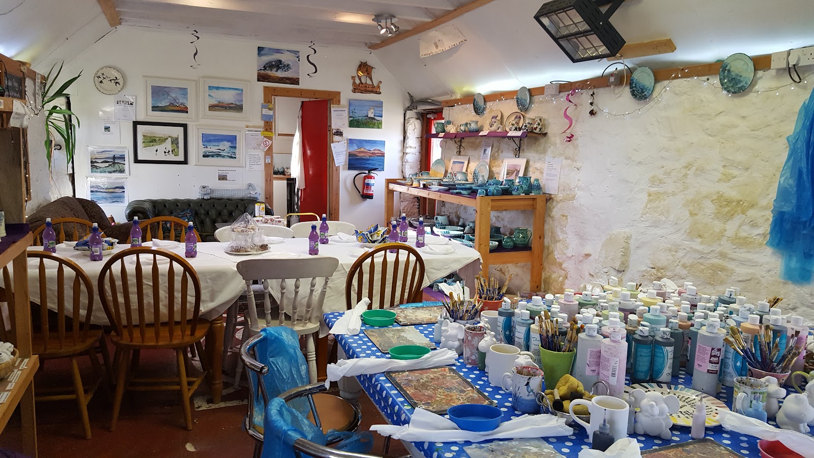 Tables laid for pottery painting at Persabus, pots and paints under the beams.