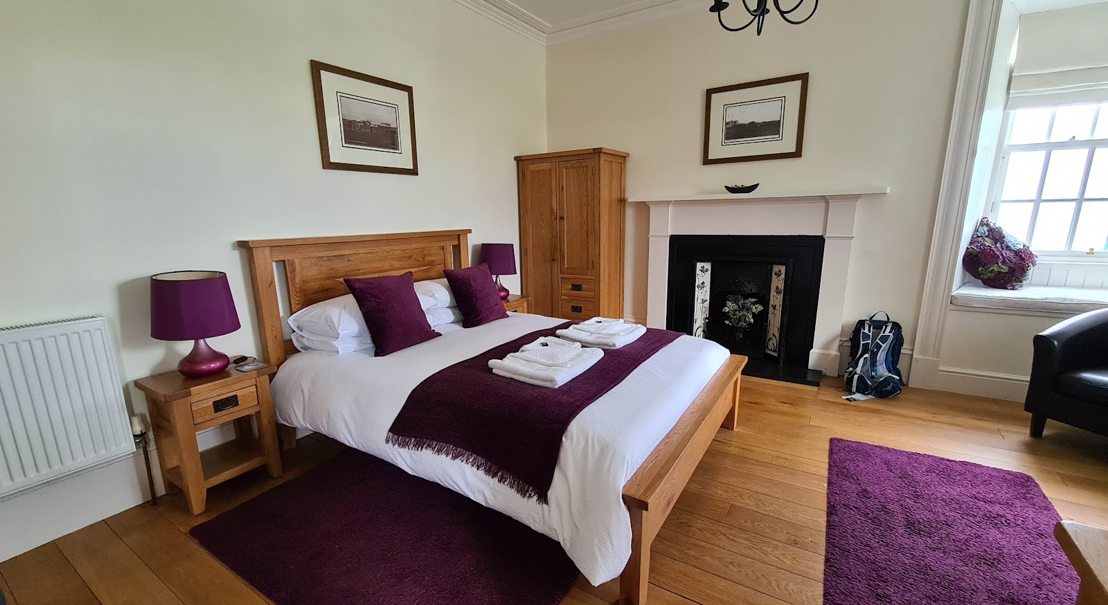 Bedroom with oak furniture, purple throws and a cast-iron fireplace