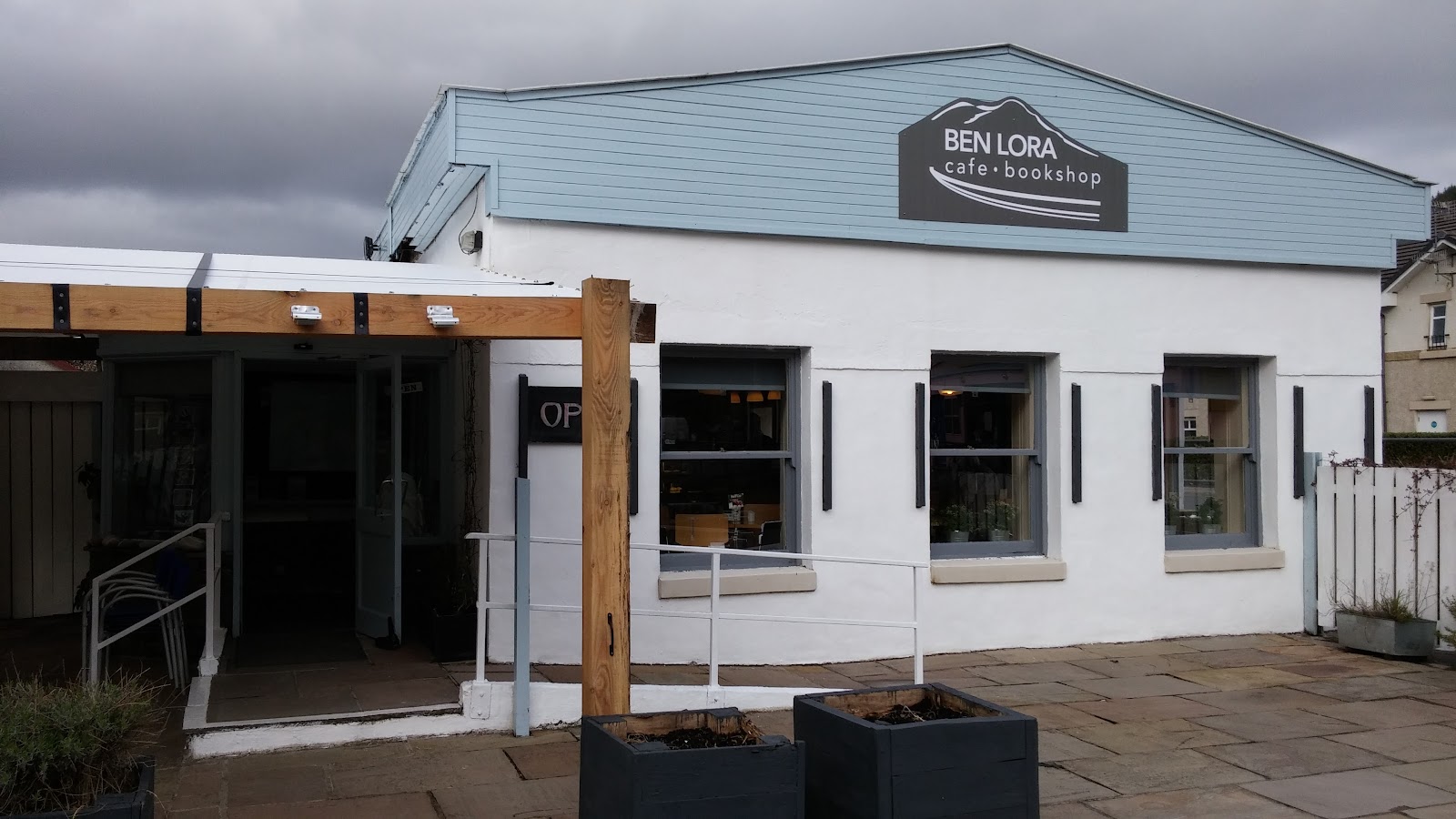 The whitewashed front of Ben Lora Cafe & Bookshop in Benderloch under a grey sky.