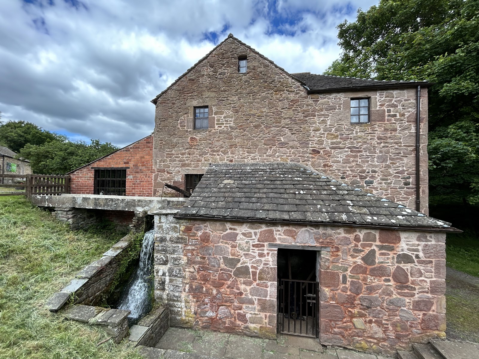 Barry Mill, a tall stone mill beside its burn among trees.