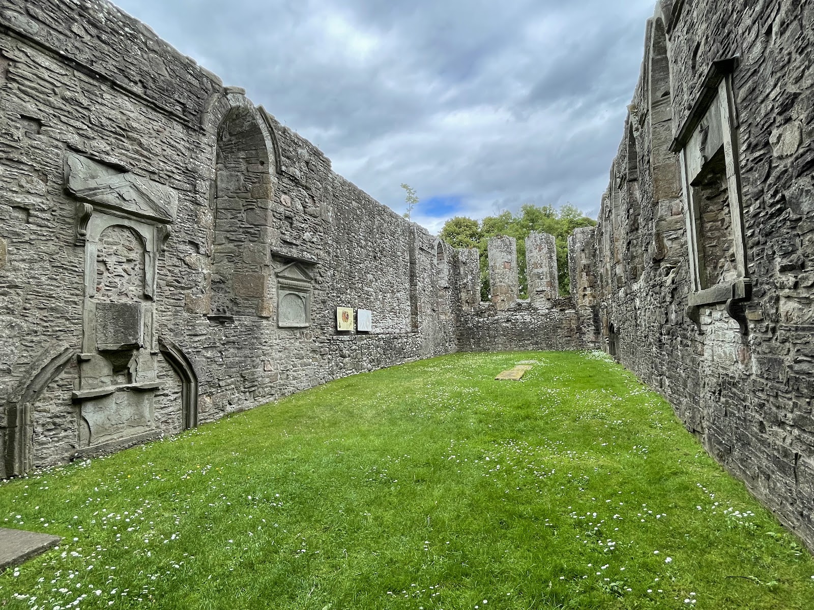 Roofless stone walls and wall tombs enclose a grassy ruined church interior