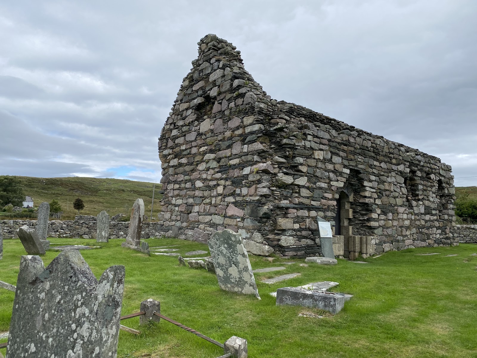 Keills Chapel, a roofed rubble chapel among old gravestones on a green rise.