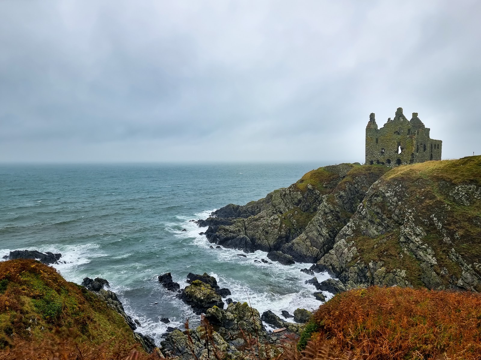 Ruined castle on a rocky clifftop above crashing waves