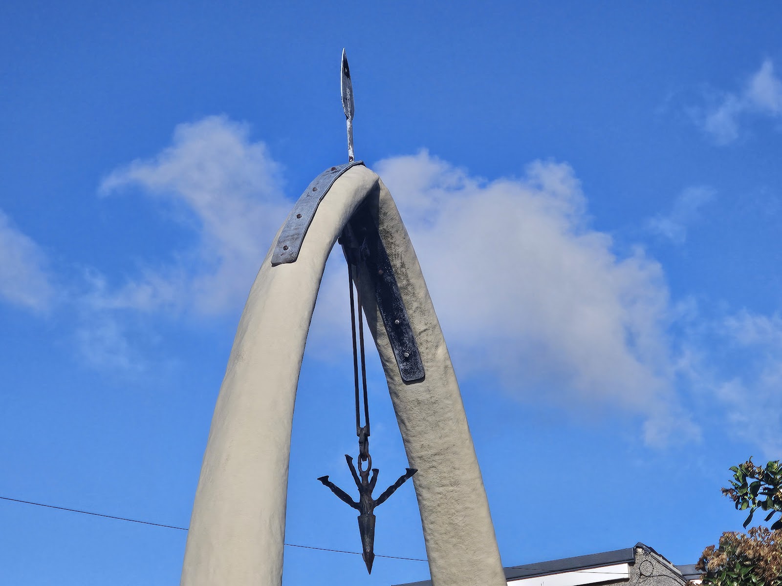 The top of the Whalebone Arch, the harpoon hanging from the bones against a blue sky.