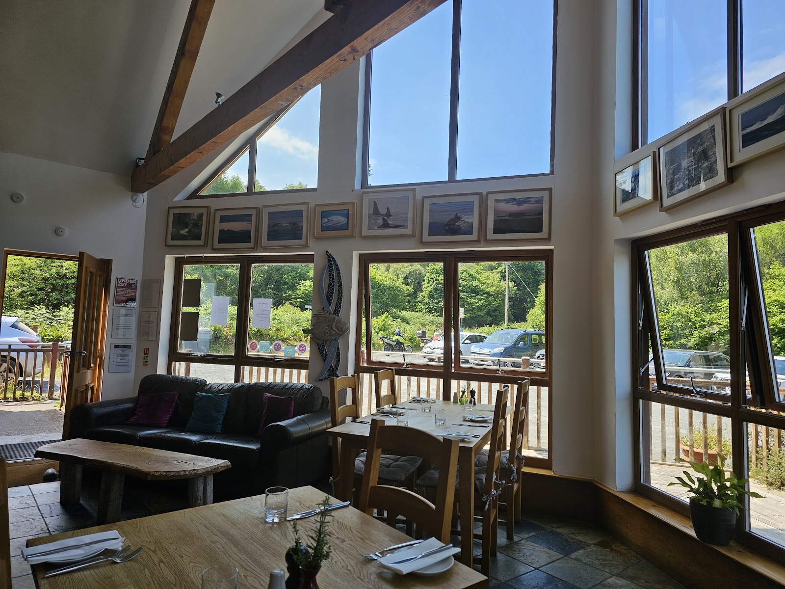 Inside Am Birlinn: tables under a high timber ceiling, big windows onto the trees.