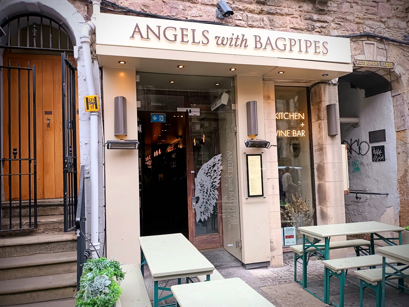 The cream front of Angels with Bagpipes on the High Street, angel wings on its glass doors.