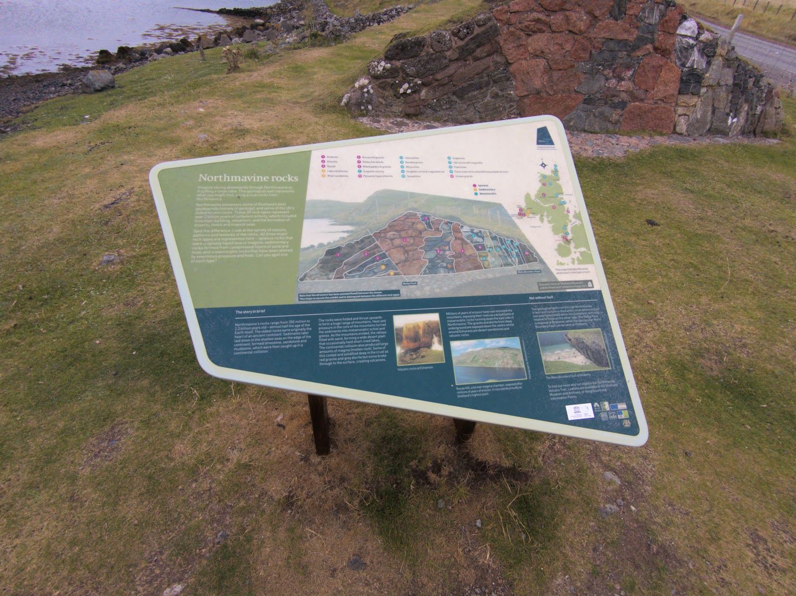 The Northmavine rocks board on the grass at Mavis Grind, red rock behind it.