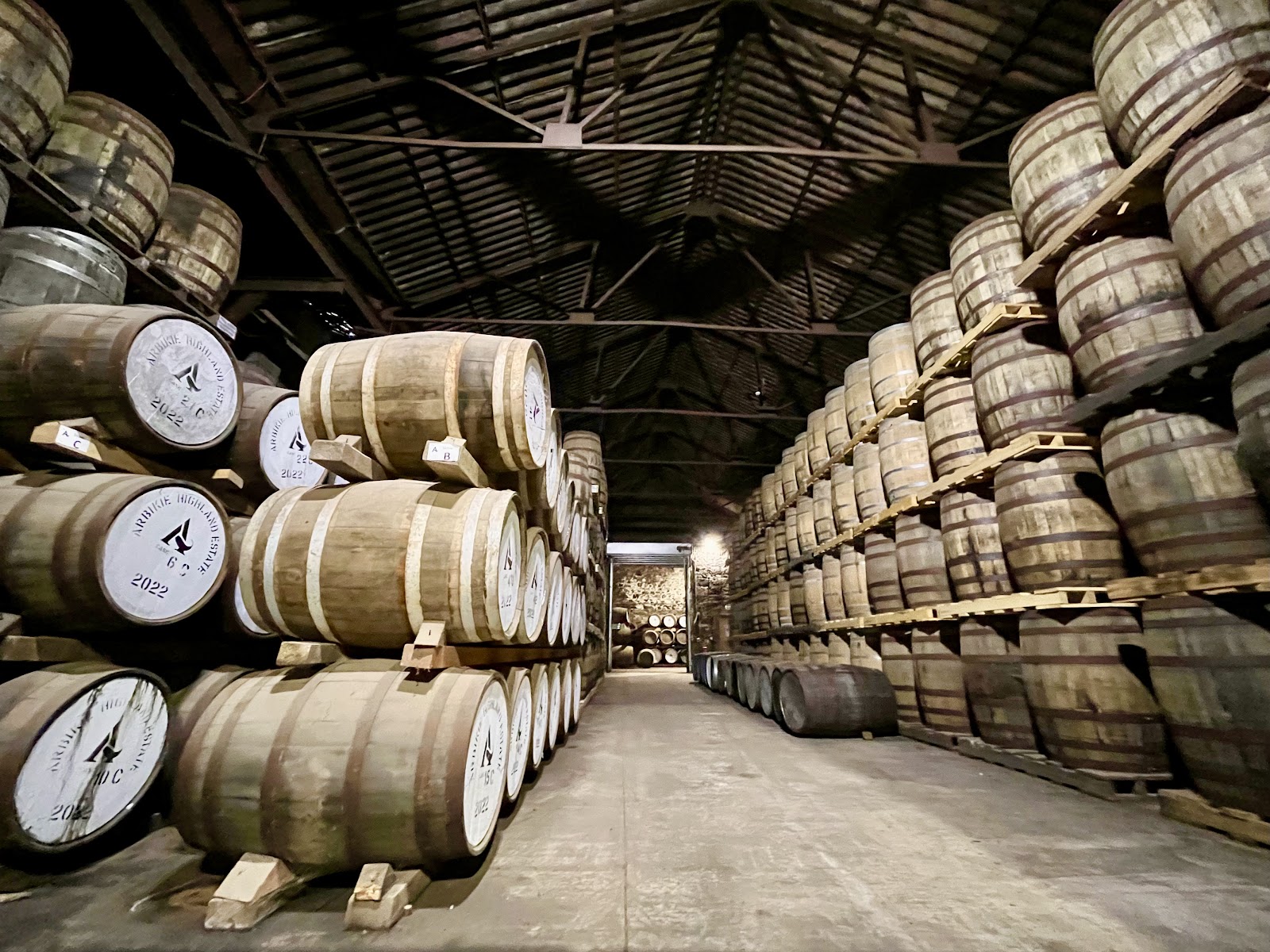 Whisky casks marked "Arbikie Highland Estate 2022" stacked in rows inside a warehouse