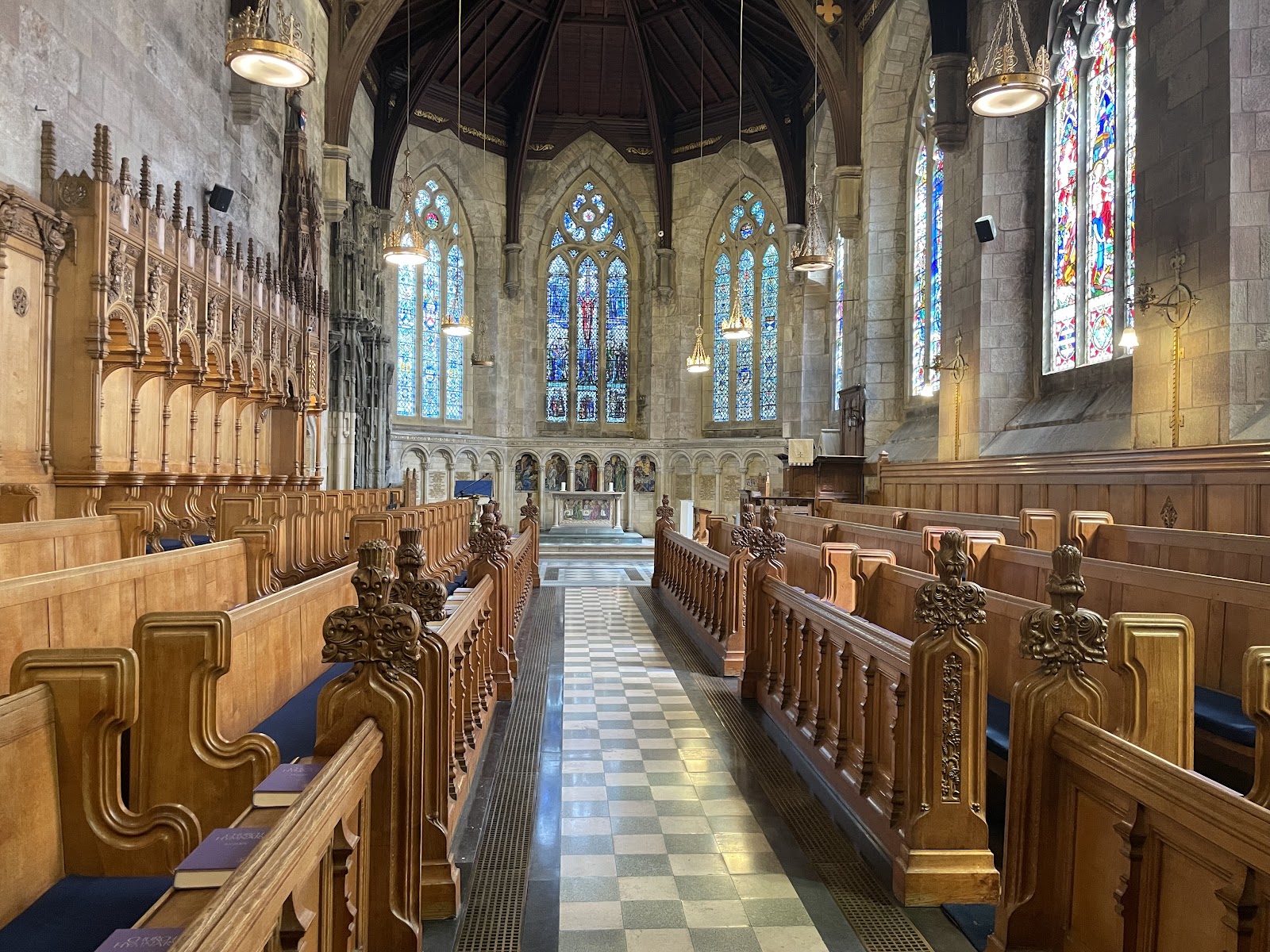 Carved wooden pews line the aisle beneath stained glass windows and vaulted ceiling