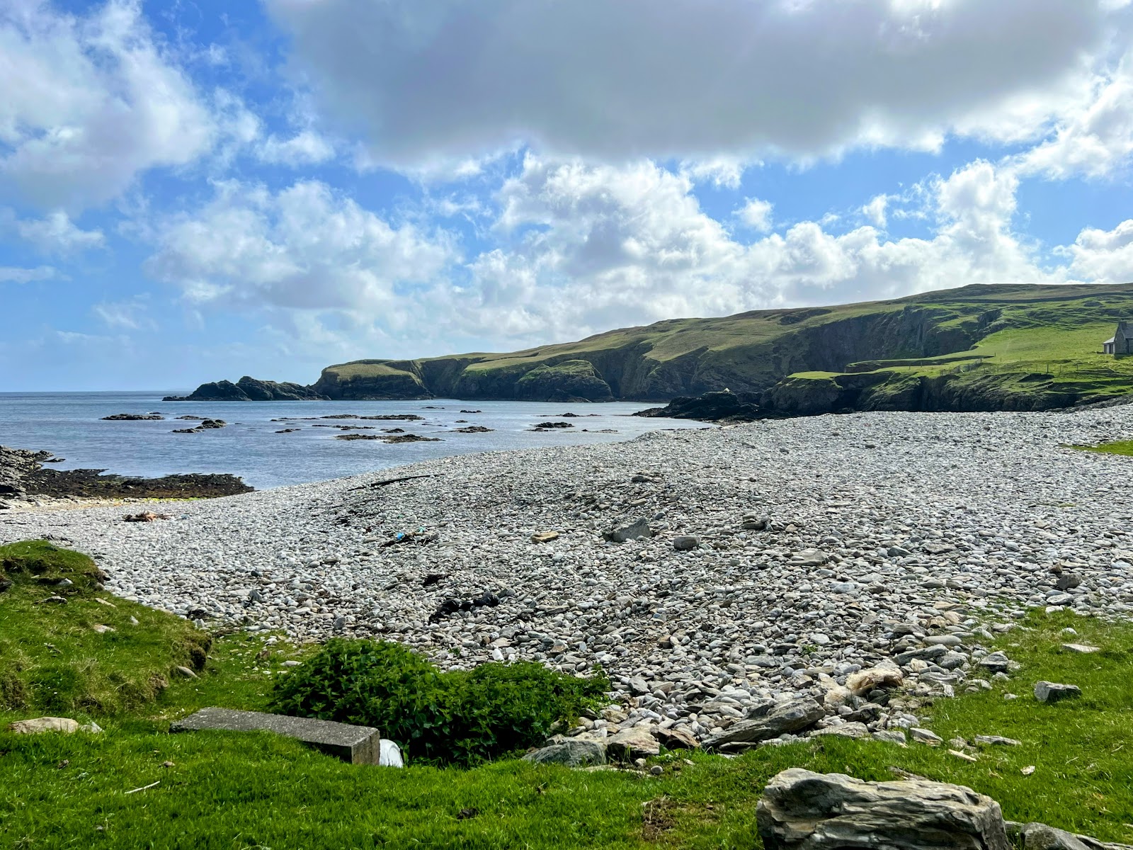 The pebble beach at Funzie Bay, Fetlar, and the green cliffs beyond.