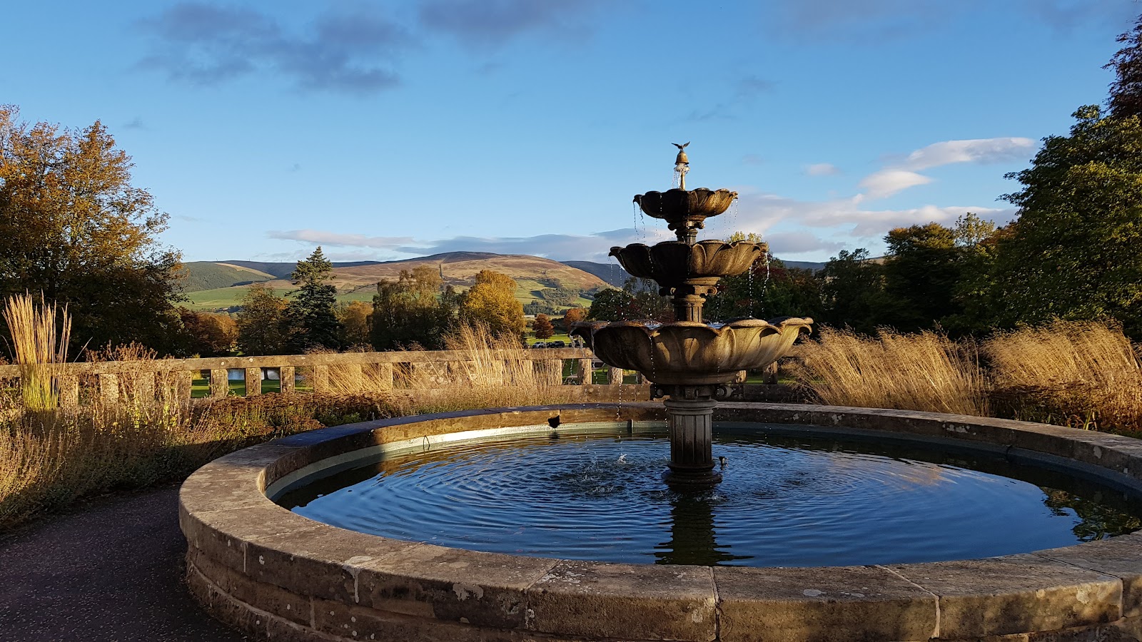 A stone fountain on the terrace at Gleneagles, the hills beyond.