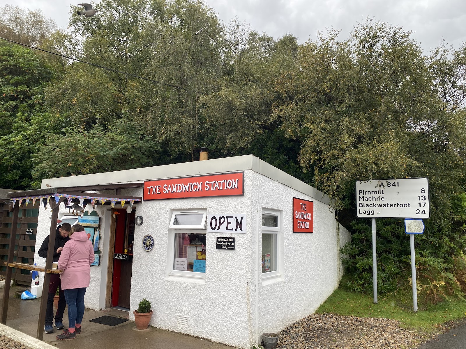 The Sandwich Station beside an A841 sign showing Pirnmill, Machrie, Blackwaterfoot and Lagg