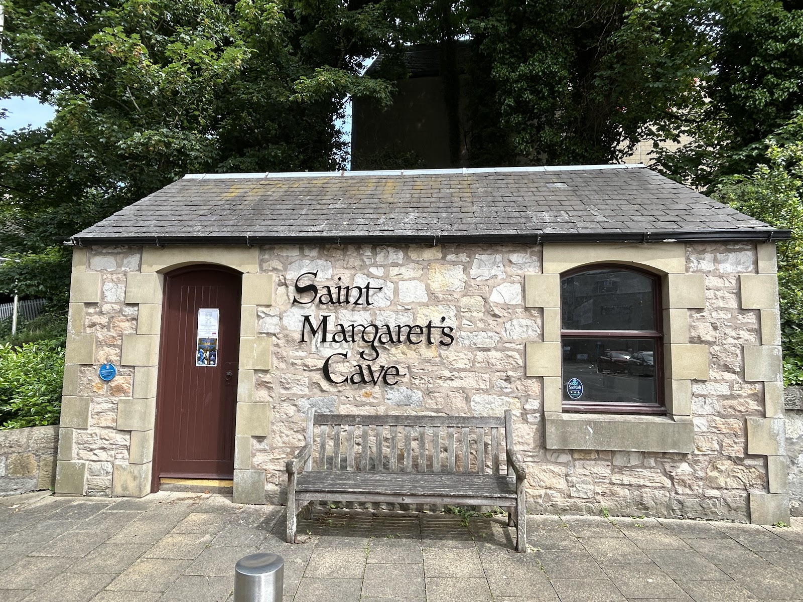 Stone entrance building with wooden bench, lettering reads "Saint Margaret's Cave