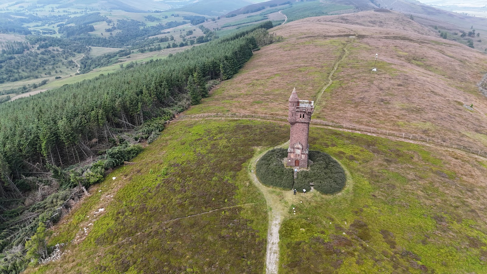 Sandstone tower on a hilltop, surrounded by heather and forestry below