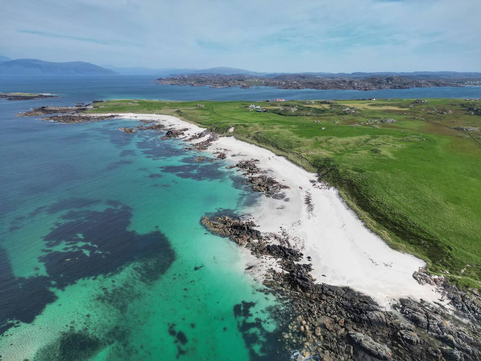 The white sand and turquoise water of Iona's north end beaches from above, green machair behind.