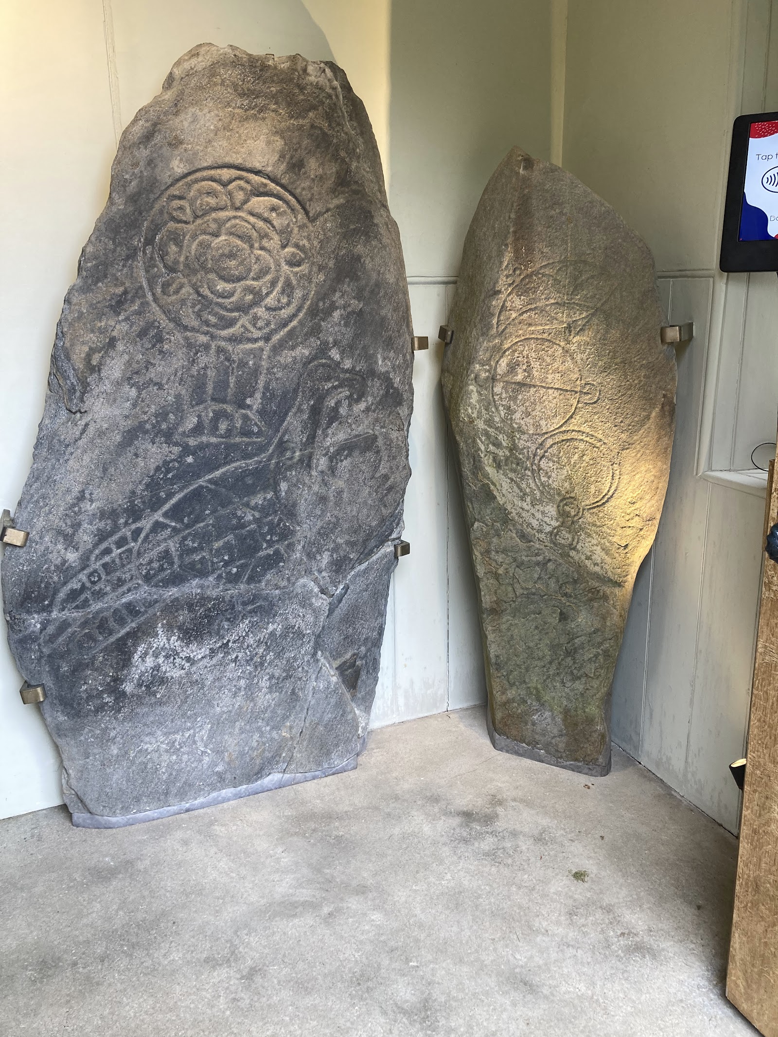 The Inveravon Pictish stones in their lit porch at the church, grey slabs carved with an eagle, discs and a crescent.