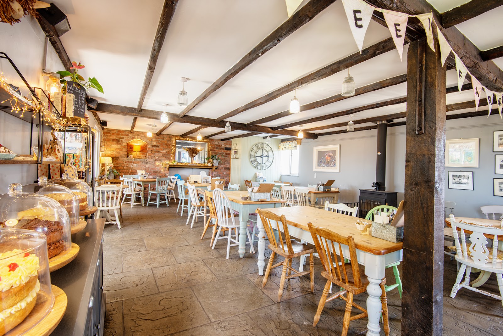 Farm café with beamed ceiling, mismatched chairs and cakes under glass domes