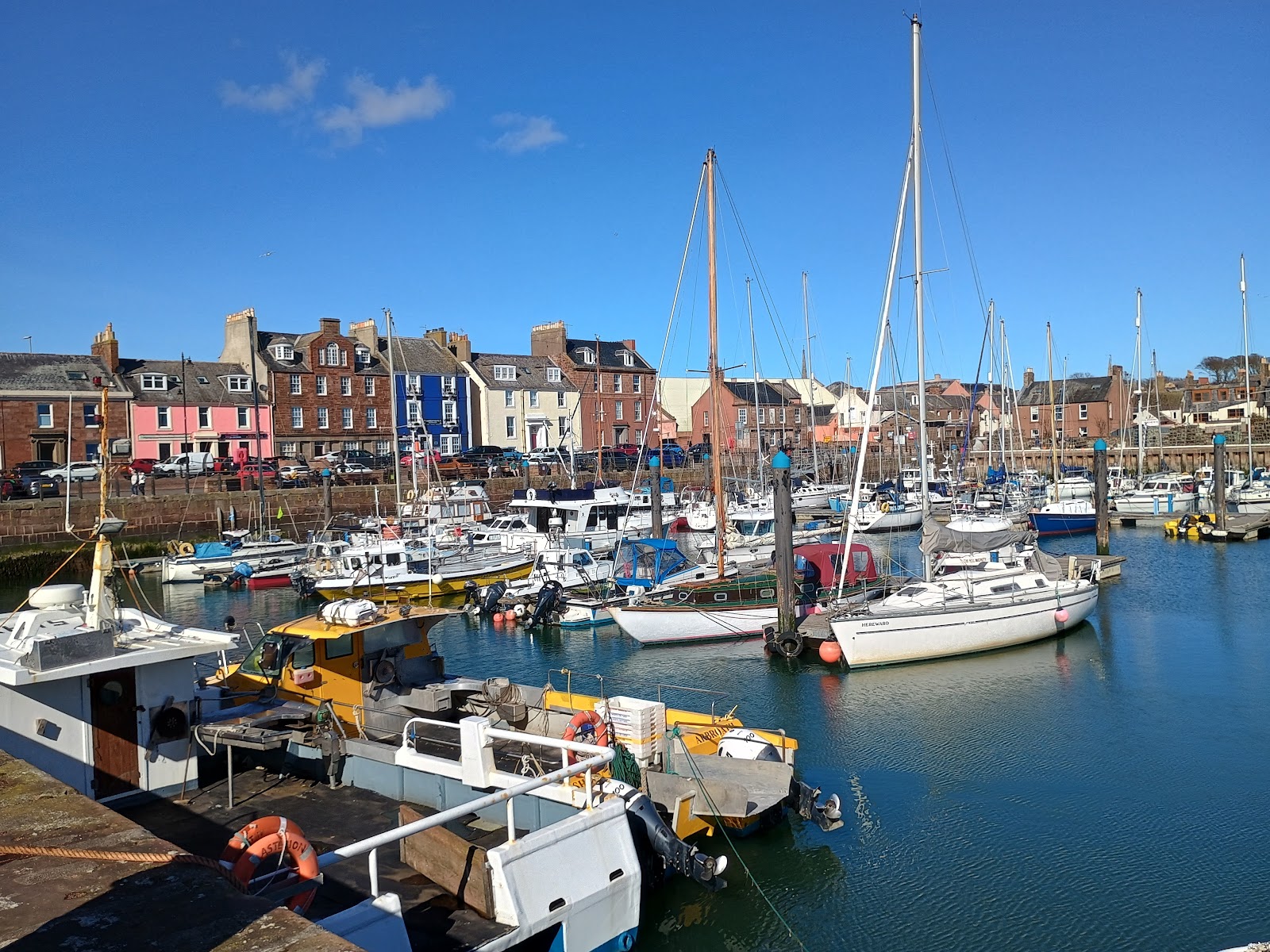 Boats in Arbroath harbour below a row of painted houses.