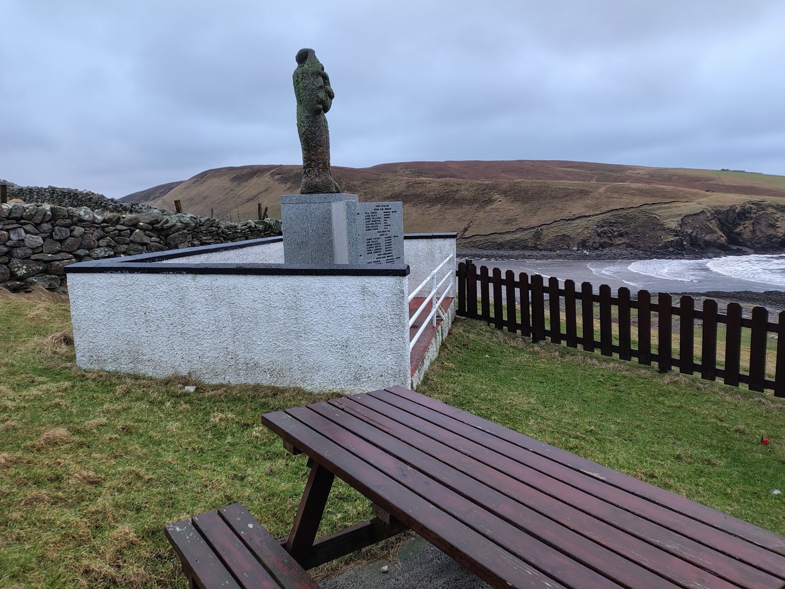 The Gloup memorial statue on its plinth above the beach at Gloup Voe.