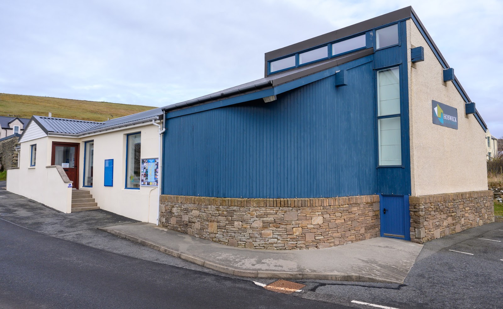 The blue and white front of the Hoswick Visitor Centre on the village street.