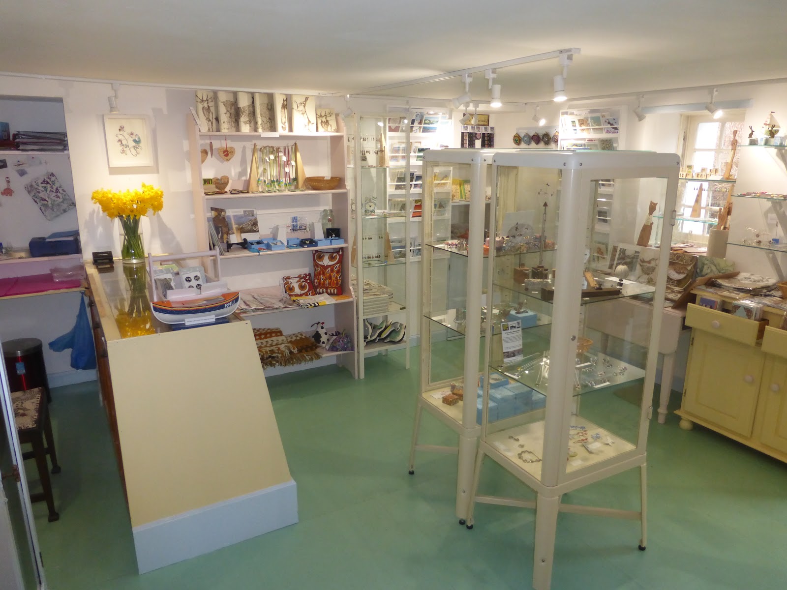 Craft shop interior with jewellery cabinets, an RNLI lifeboat model and daffodils on the counter
