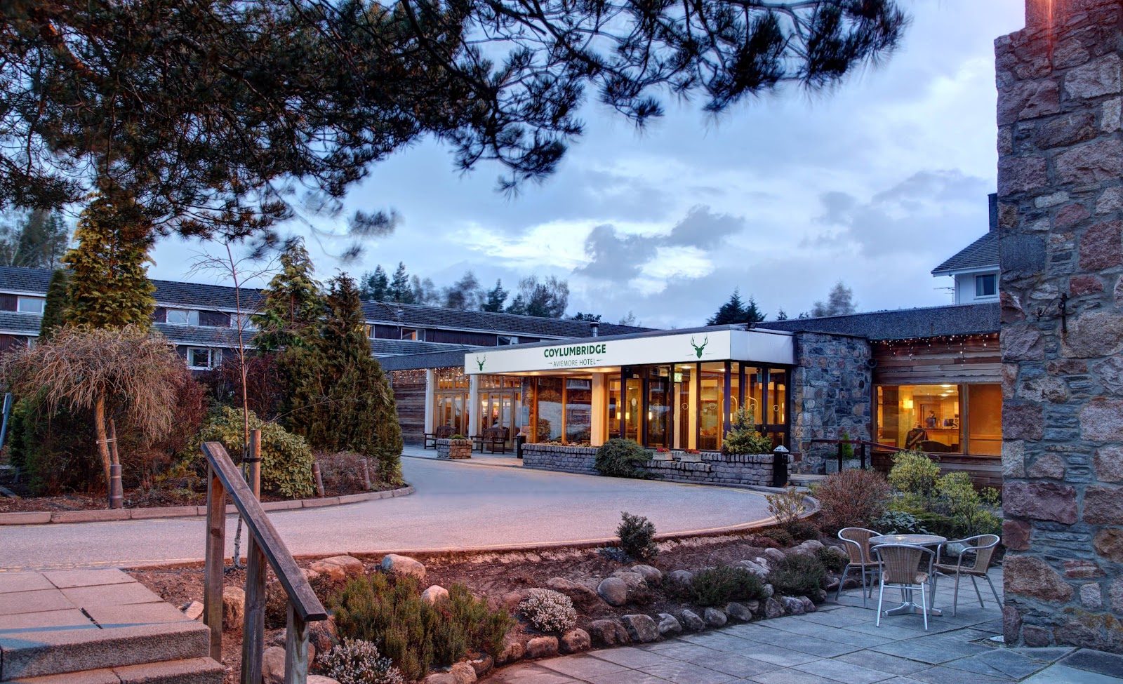 Coylumbridge Aviemore Hotel entrance lit up at dusk, surrounded by pine trees