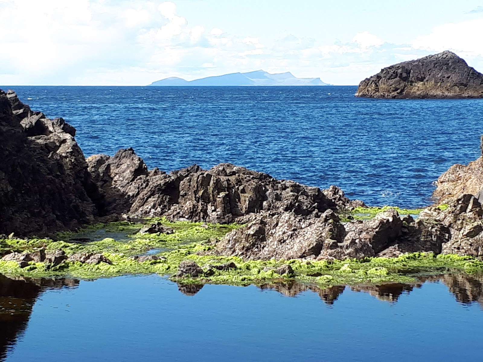 Rocks and pools on the coast near Culswick, Foula on the horizon.