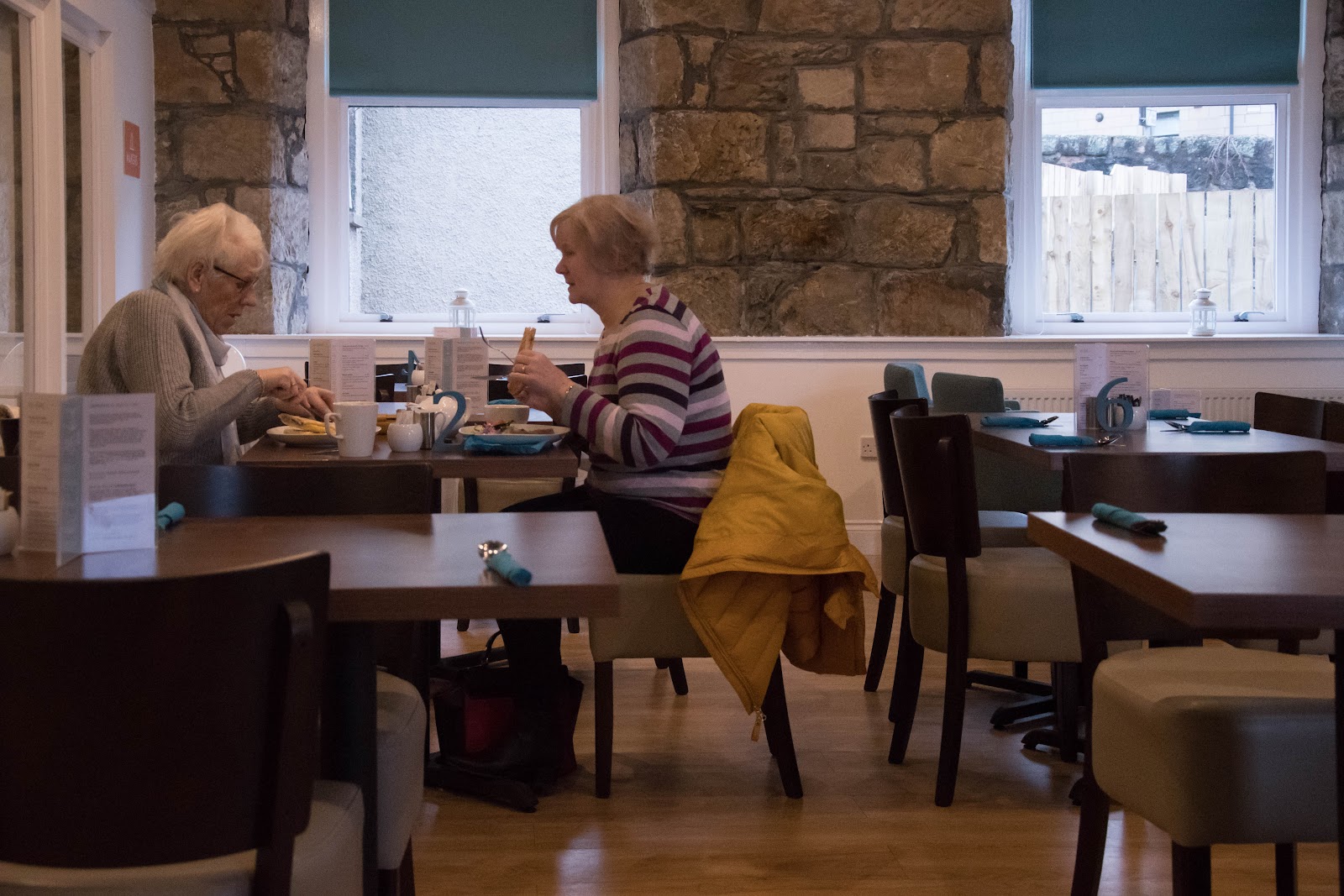Diners at tables in the café's stone-walled room.