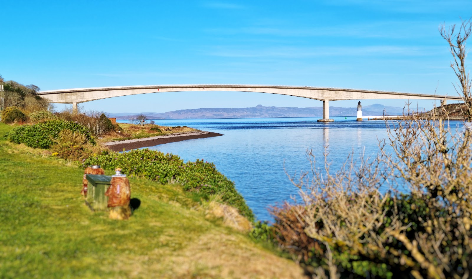 Skye Bridge arches over the strait, with a lighthouse beside its pier