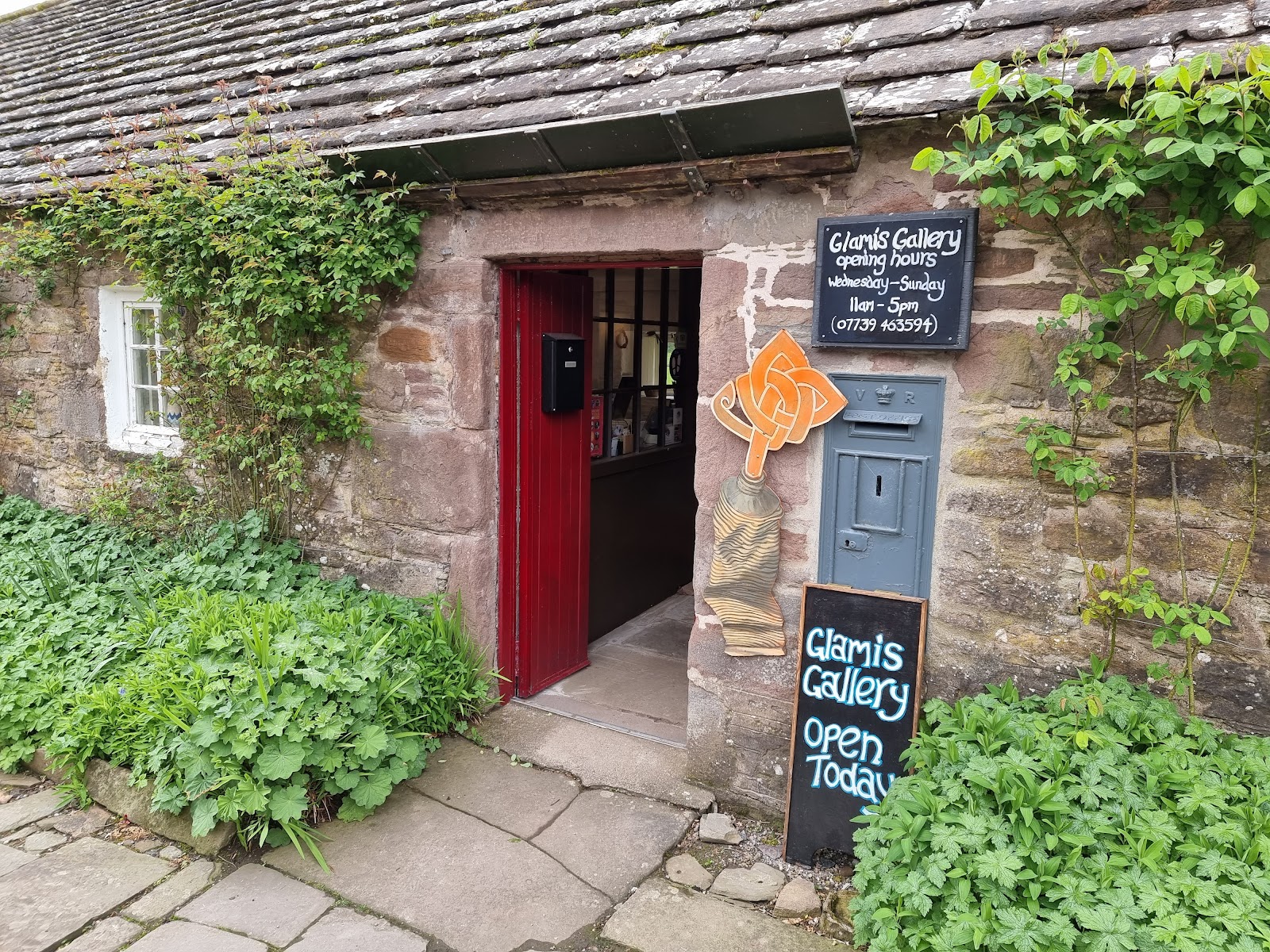 The red door of Glamis Gallery among the ivy of the old cottages.