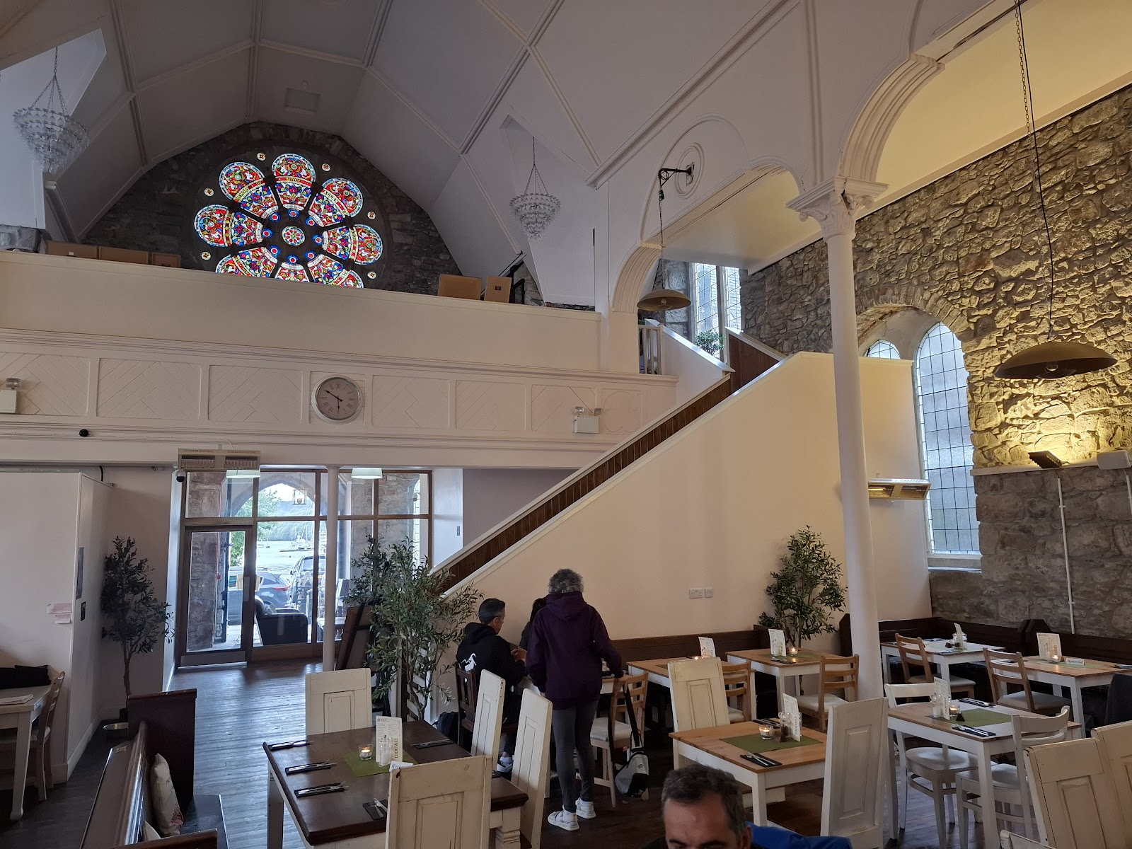 Inside The Galleon: white walls, a high ceiling with a round window, tables and a staircase.