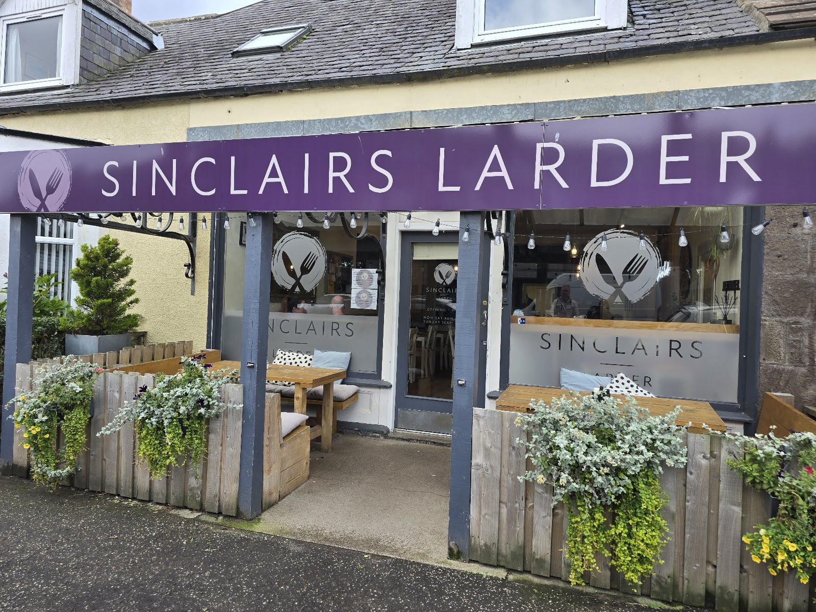 Sinclair's Larder's purple shopfront and planted terrace on Edzell High Street.