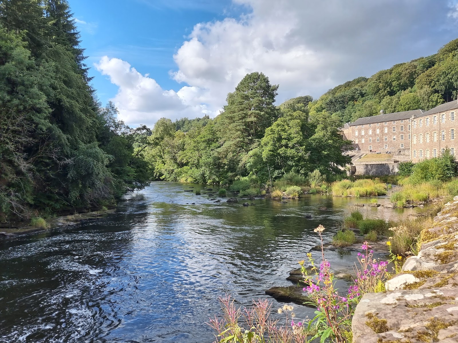 River Clyde flowing past New Lanark's mill buildings and wooded banks